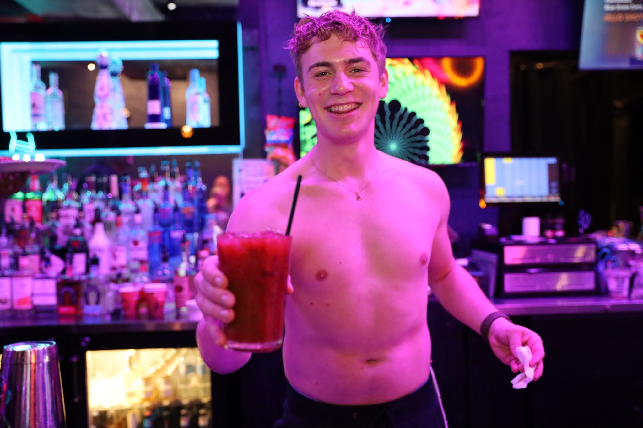 Man holding a Bloody Mary in a bar with neon lights