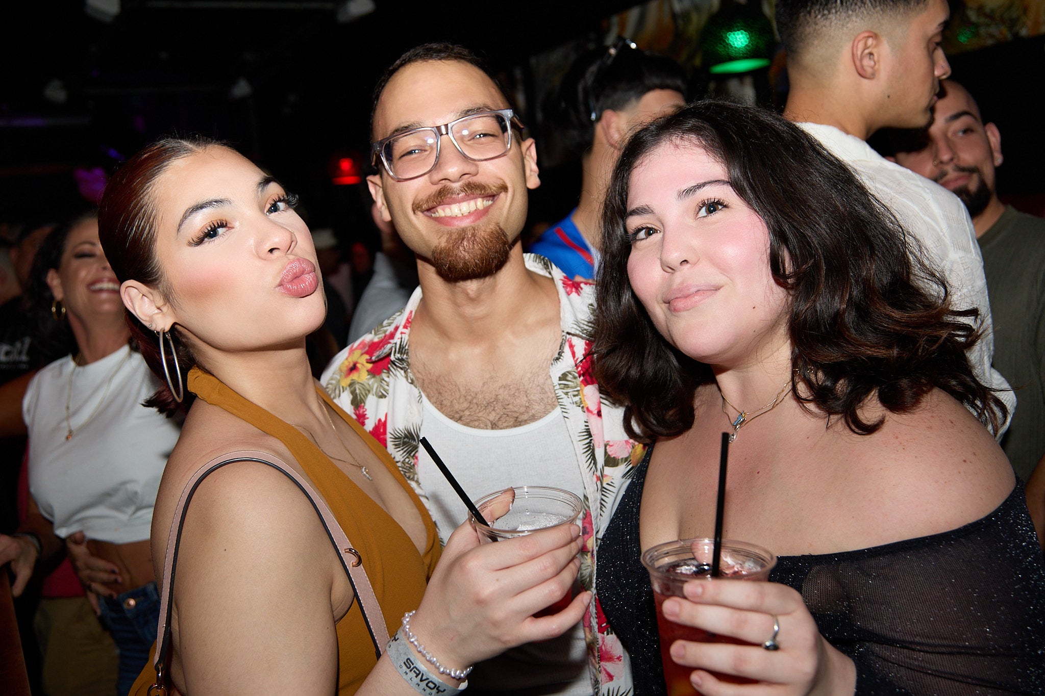 Three people at a party, two women and one man, enjoying drinks.