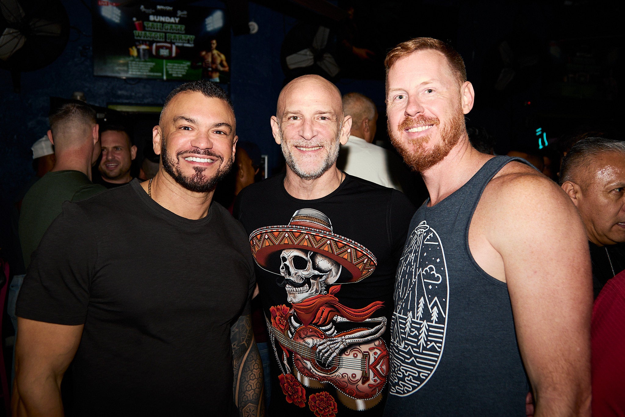 Three men posing together at a social event with a dark background