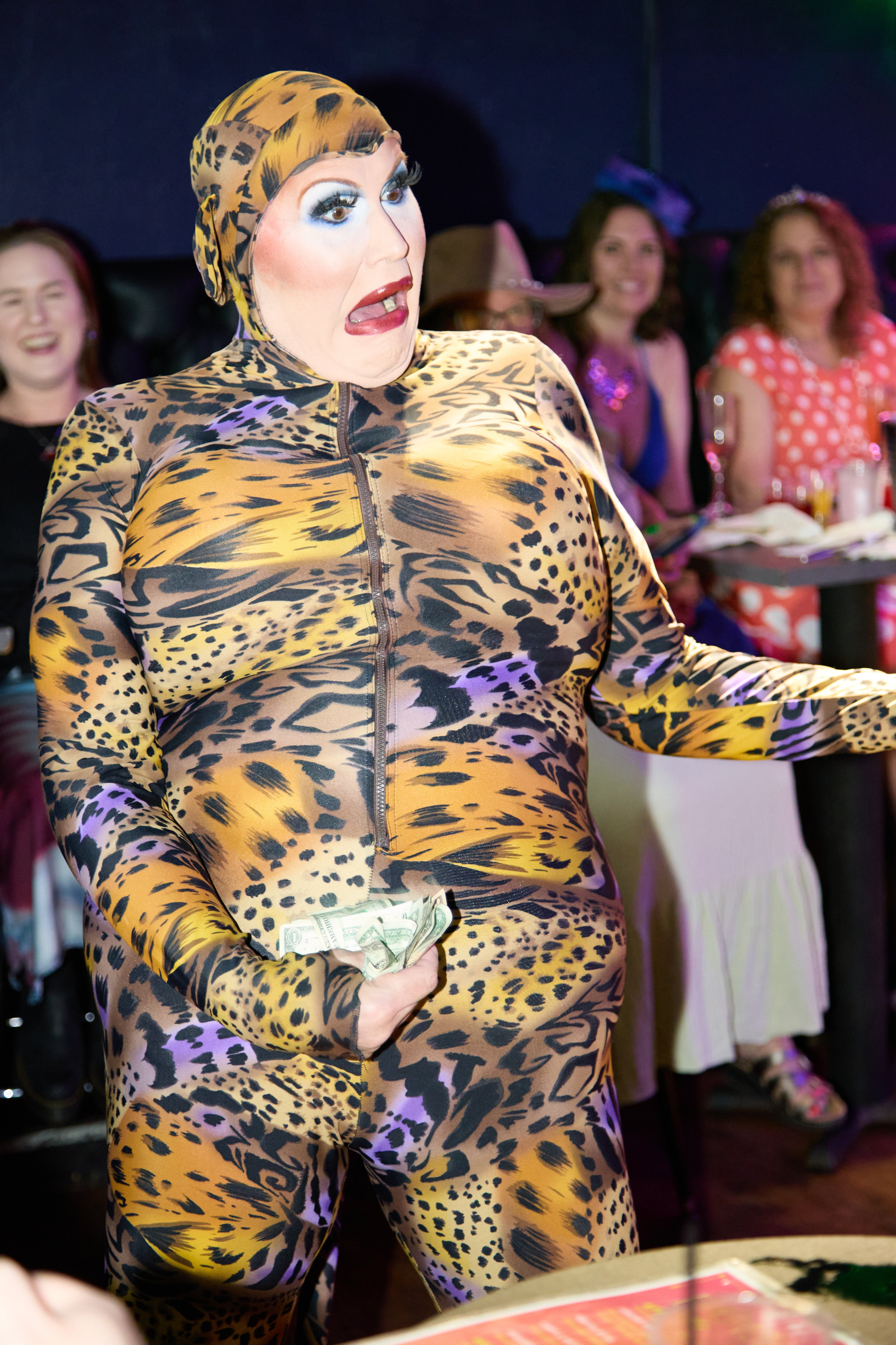 Person wearing a leopard print bodysuit with a hood in a social setting.
