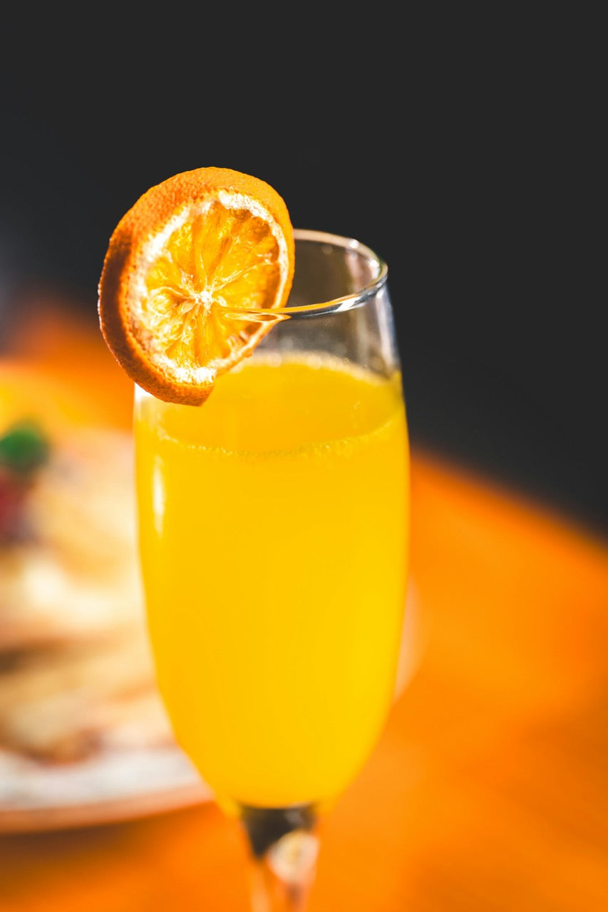 Glass of orange juice with an orange slice on a blurred background