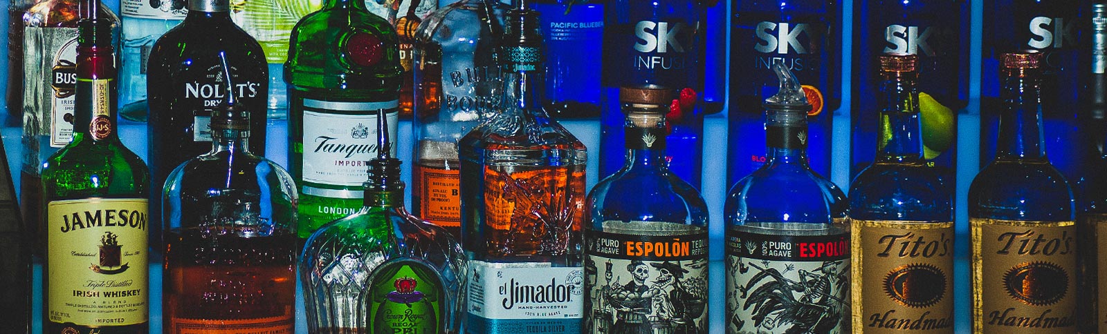 Row of various liquor bottles with labels on a blue background